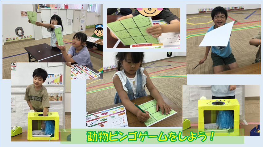 Group of children in a classroom playing animal bingo, holding green bingo cards and writing.