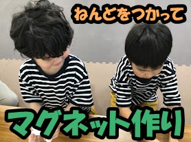 Two children in striped shirts sit at a table, crafting magnets with clay for a DIY project.