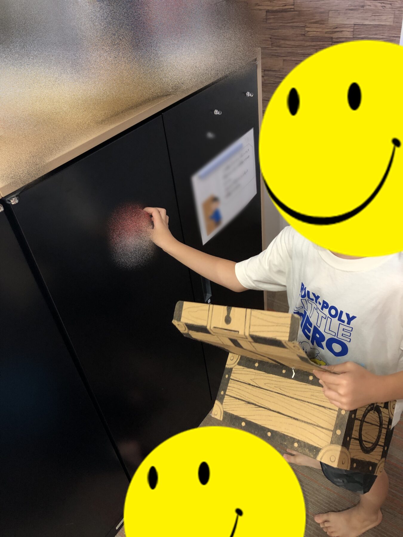 Child with a blurred or covered face reaching to open a dark locker in a hallway while holding a cardboard box.