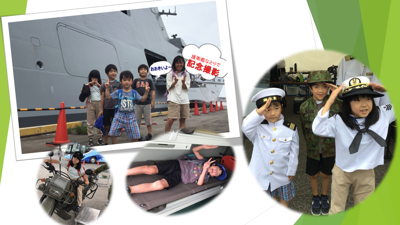 Group of children posing in front of a large gray ship; some wear naval uniforms and salute behind an orange cone line.