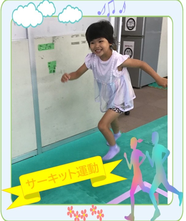 Young girl in a white dress runs on a green gym floor indoors, smiling, with a yellow ribbon displaying 'サーキット運動' (circuit exercise) and decorative border elements like clouds and dancing silhouettes.