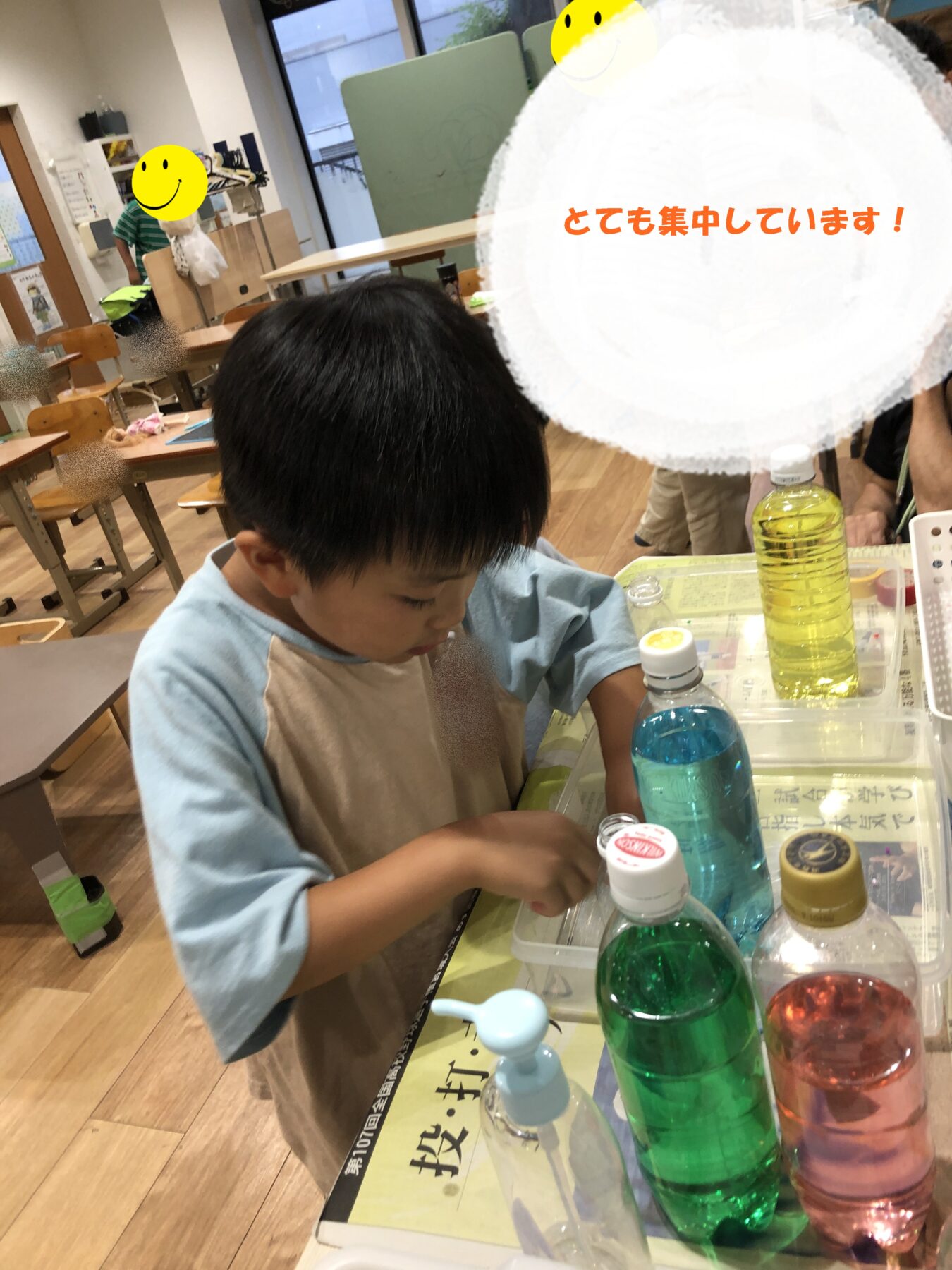 A young child concentrates on a science activity at a classroom table with colorful bottles and liquids nearby.