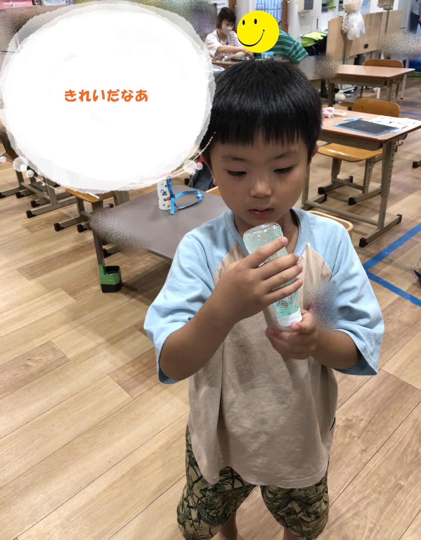 Boy in a classroom holds a bubble solution bottle, looking at it thoughtfully.