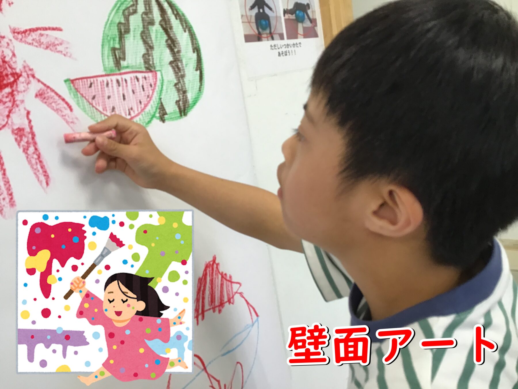Young child draws with pink chalk on a white wall beside a large green watermelon illustration and a colorful poster showing a girl painting.