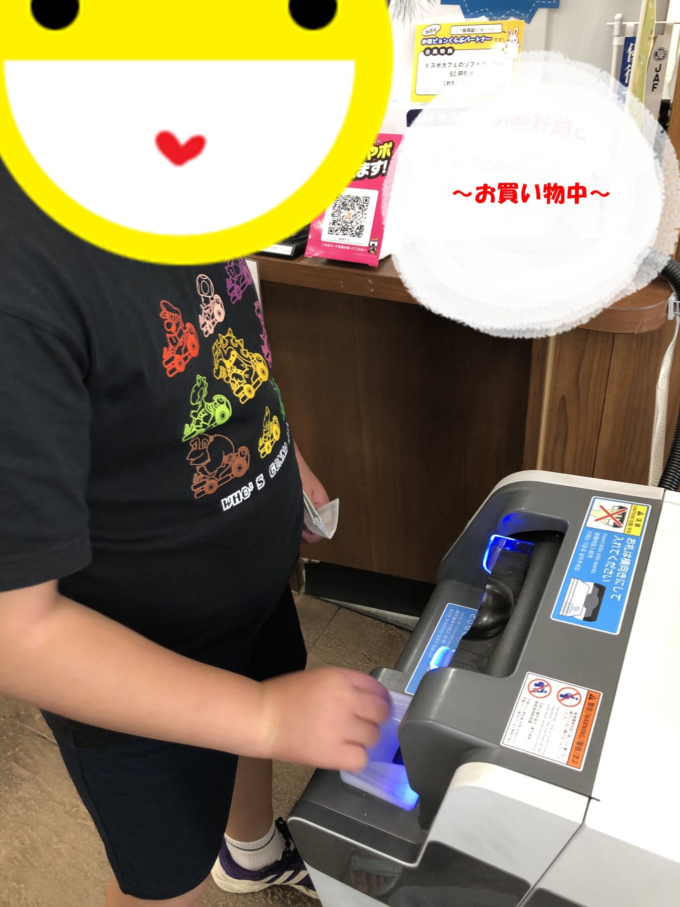 Person at a checkout using a card reader to pay for a purchase, with a large yellow emoji graphic obscuring part of the view.