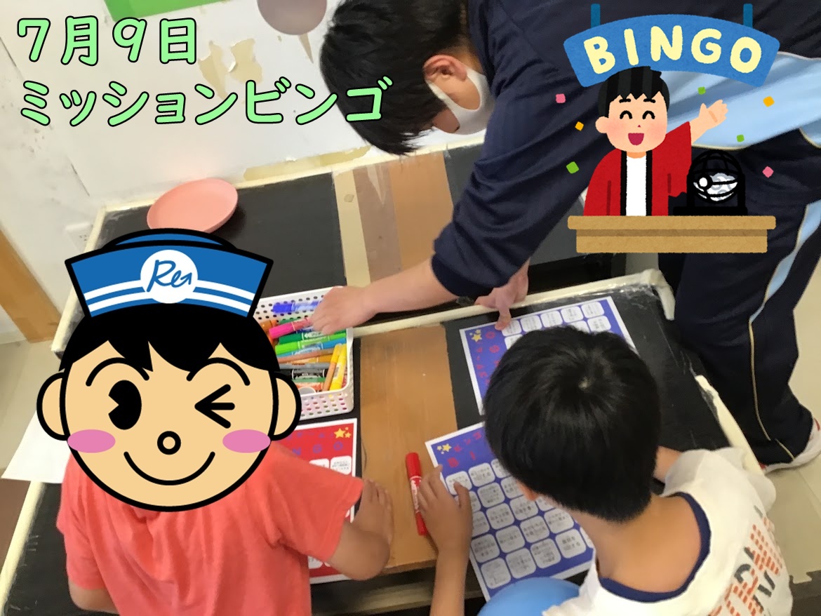 Classroom scene: kids at a table playing a July 9 mission bingo activity with bingo cards and markers; Japanese banner text reads '7月9日 ミッションビンゴ'