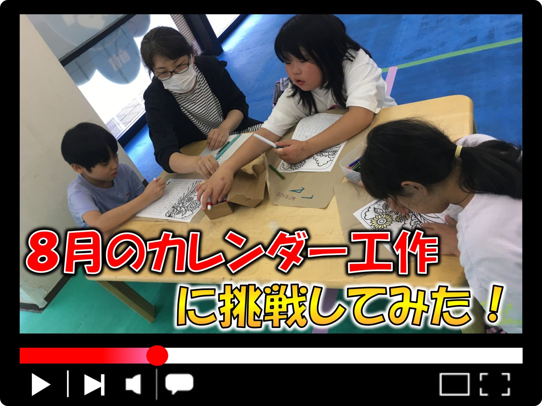 Children and a teacher coloring calendars at a table with markers and worksheets in a classroom.