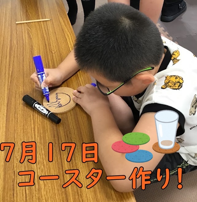A young boy with glasses colors a round cork coaster with a blue marker on a wooden table.