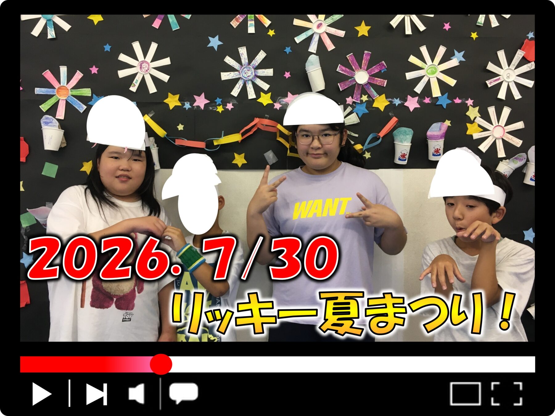 Three children pose in front of a black craft wall covered in star decorations and paper art; large white shapes cover their heads, with bold red and yellow text across the bottom