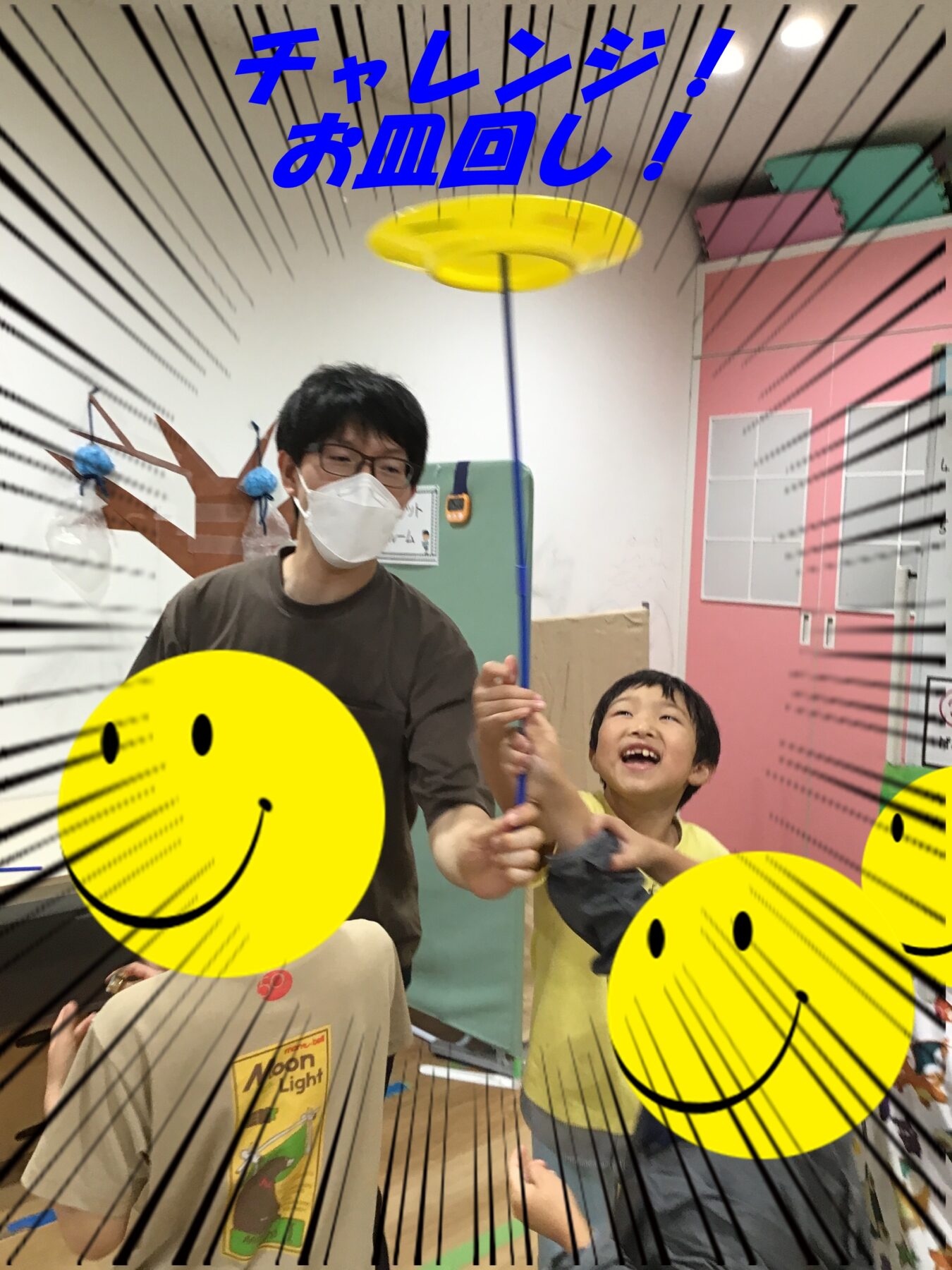 Adults and kids in a colorful room hold a rotating plate on a stick as a fun activity; bold Japanese caption says 'Challenge! Plate spinning!' with comic-style lines and smiley graphics.