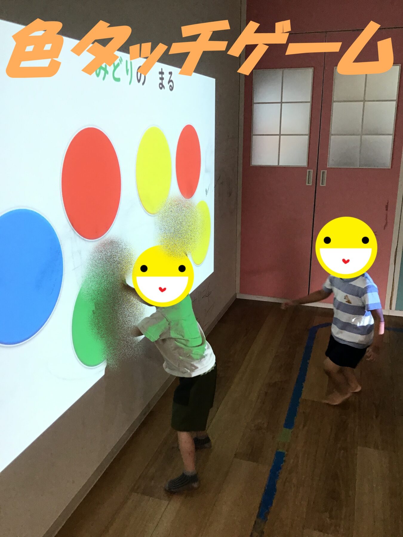 Children interact with a wall display of large colored circles (red, yellow, blue, green) as part of a color activity in a classroom.