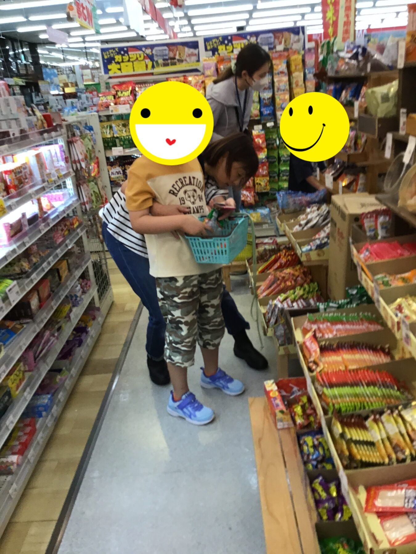 Two children in a crowded grocery store aisle, one holding a small blue shopping basket while an adult assists nearby.