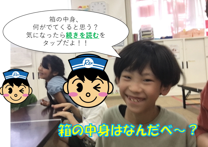 教室で笑顔の子どもたちが箱の中身を推測する遊びをしている。吹き出しとキャラクターのイラスト入り。