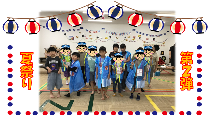 Group of children in blue festival costumes posing for a summer festival photo in a decorated hall with paper lantern garland; side banners read 夏祭り and 第2弾.