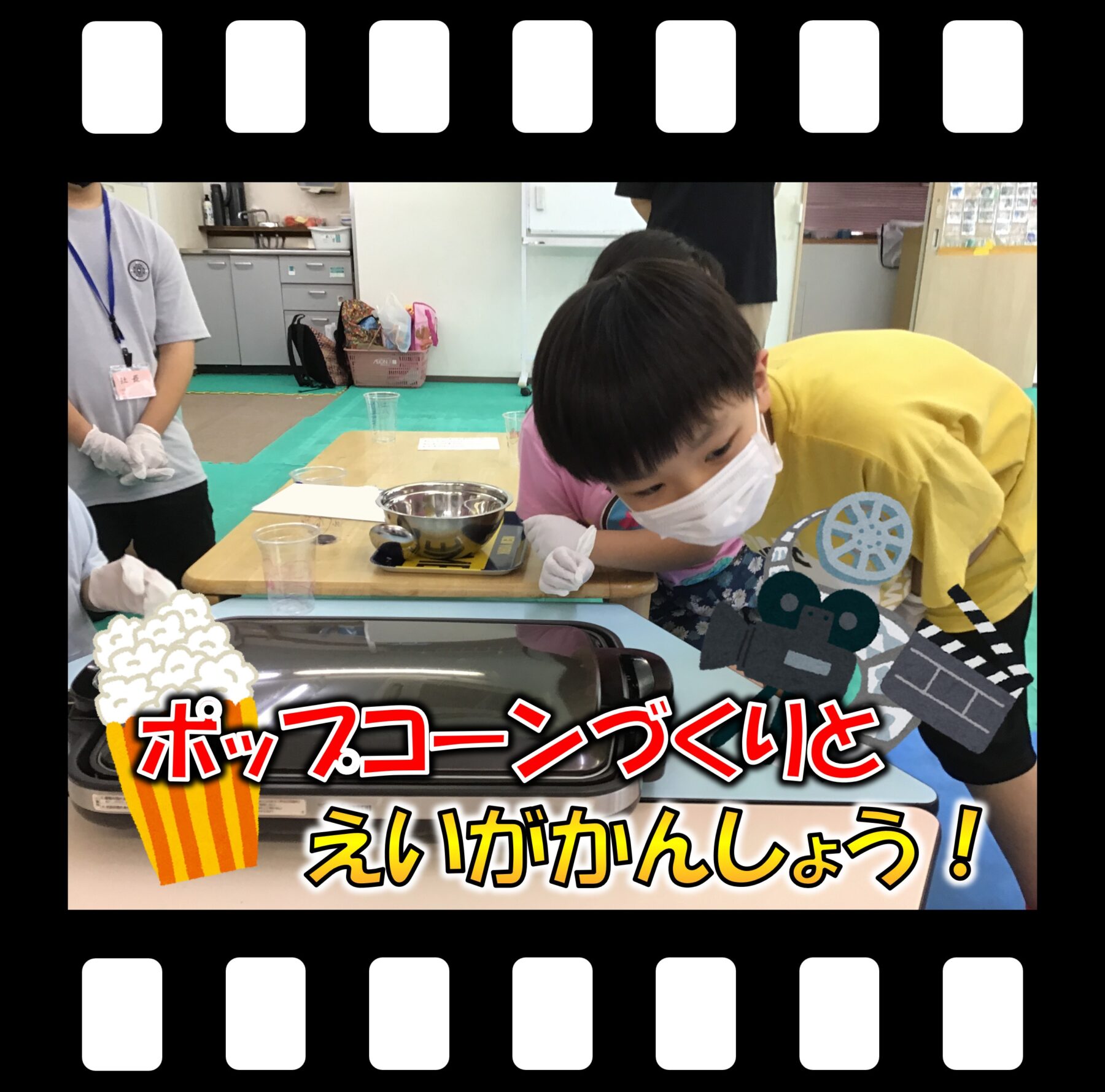 Children in a classroom wearing masks and gloves, gathered around a table with popcorn-making equipment.