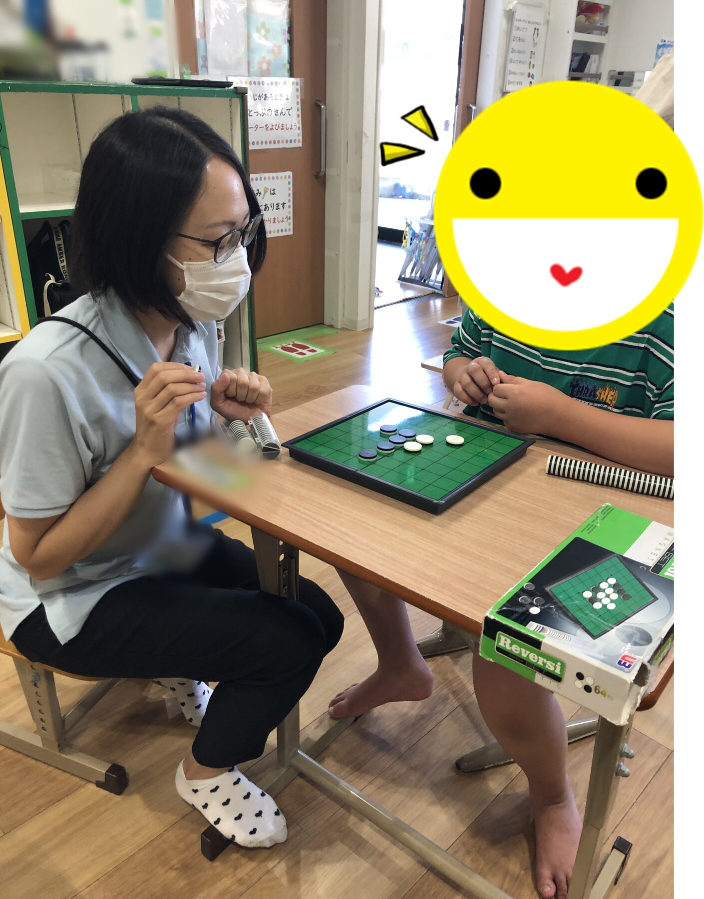 Woman in a mask and glasses plays Reversi with a child across a green game board on a wooden table in a bright room.