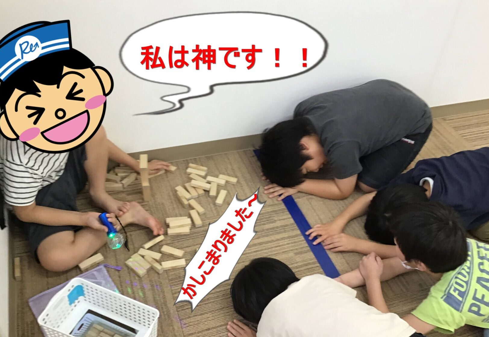 Children sitting on a carpeted floor, building with wooden blocks; scattered blocks and a blue tape line nearby, with a cartoon sticker on the left and Japanese text overlays.