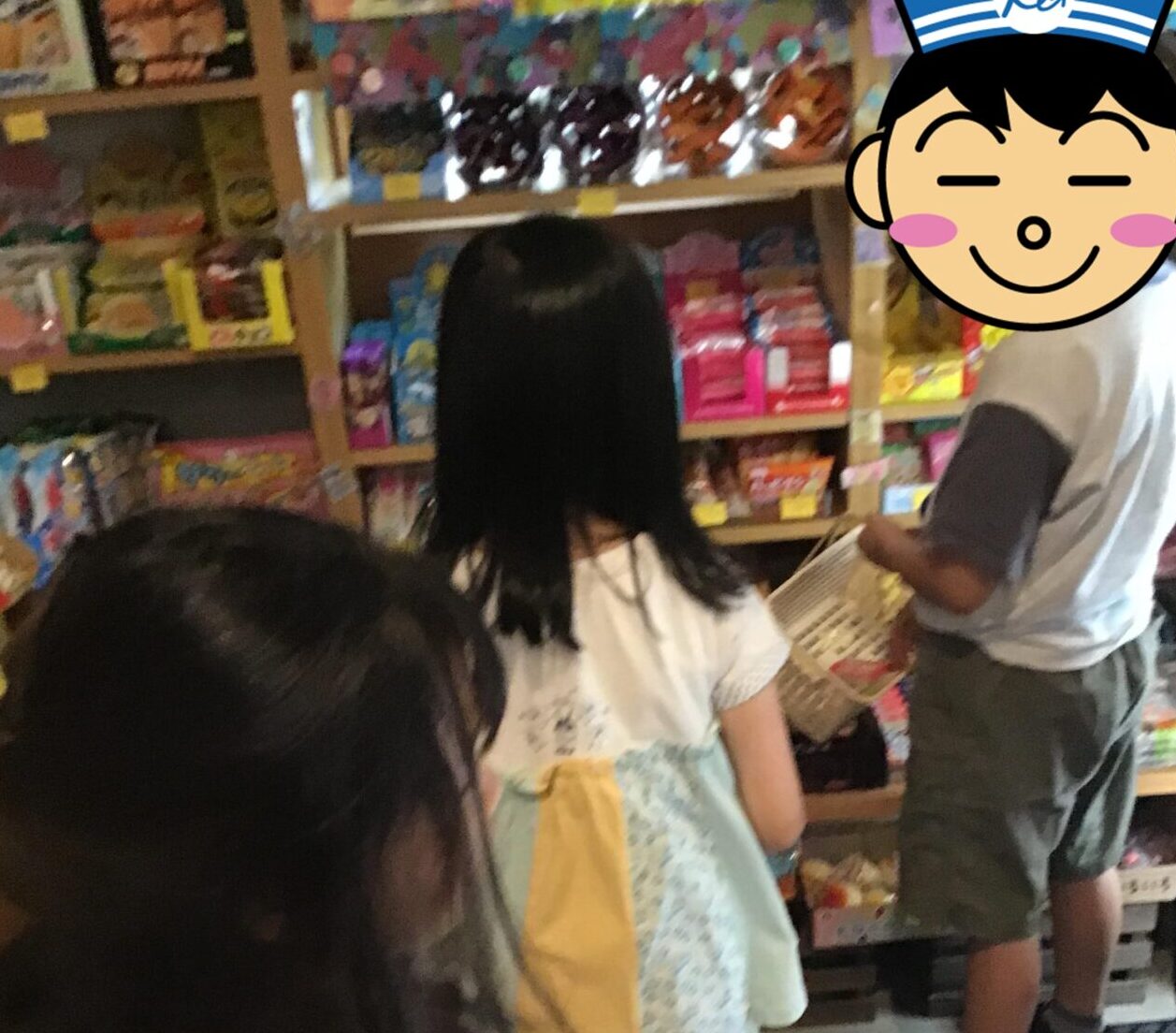 Children in a colorful toy store aisle, browsing shelves full of boxes, with baskets in hand as they shop.