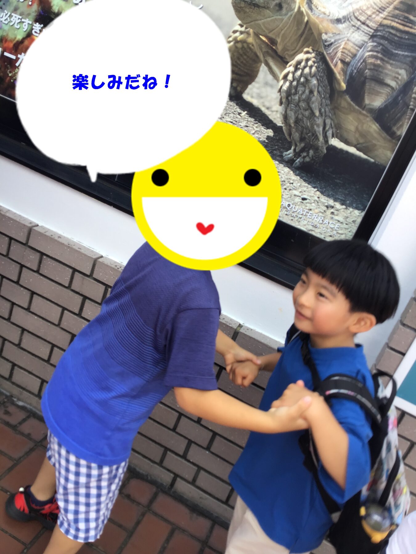 Two kids in blue shirts shake hands and smile outside near a dinosaur display, with a speech bubble reading '楽しみだね！'