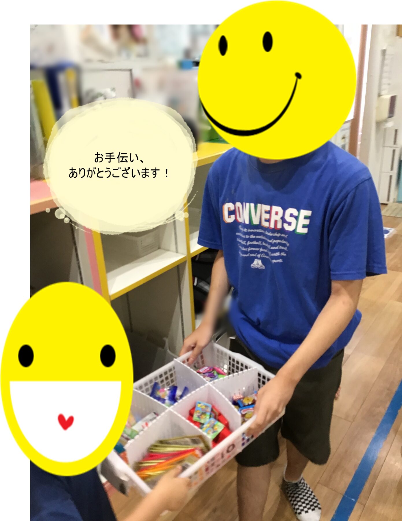 Person in a blue shirt hands out candies from a divided basket; foreground and heads covered with large yellow smiley overlays, Japanese text bubble thanking helpers.
