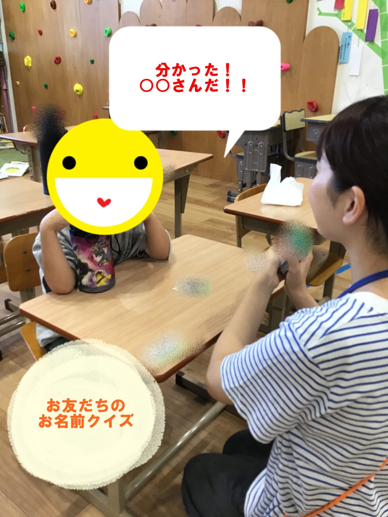 Classroom scene with a student wearing a large yellow emoji over the face; a speech bubble in red Japanese text and a circular quiz banner are visible on a desk-side board.