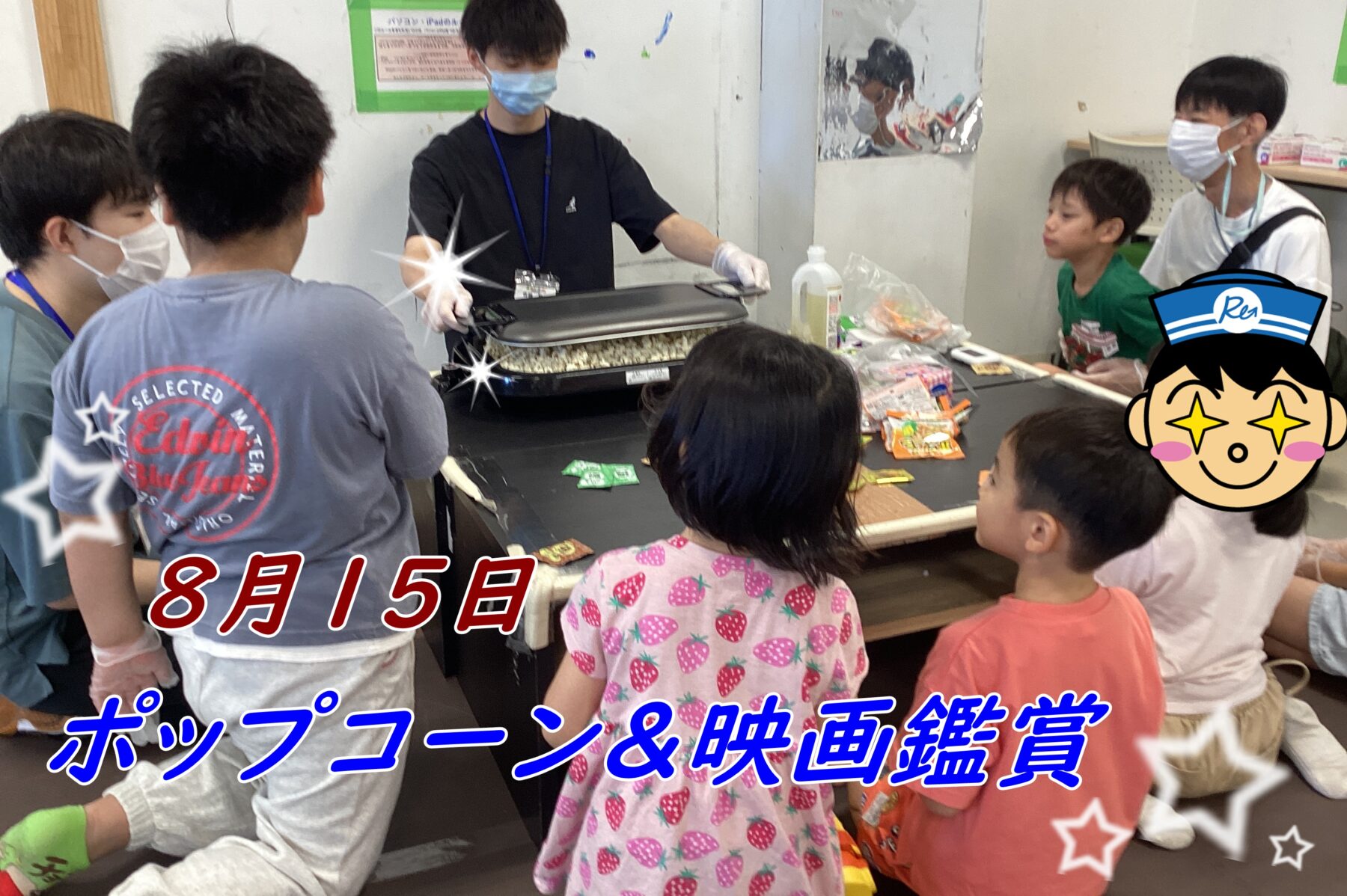 Group of children gathered around a man popping popcorn on a hot plate at a classroom table; snacks and drinks on the table nearby.