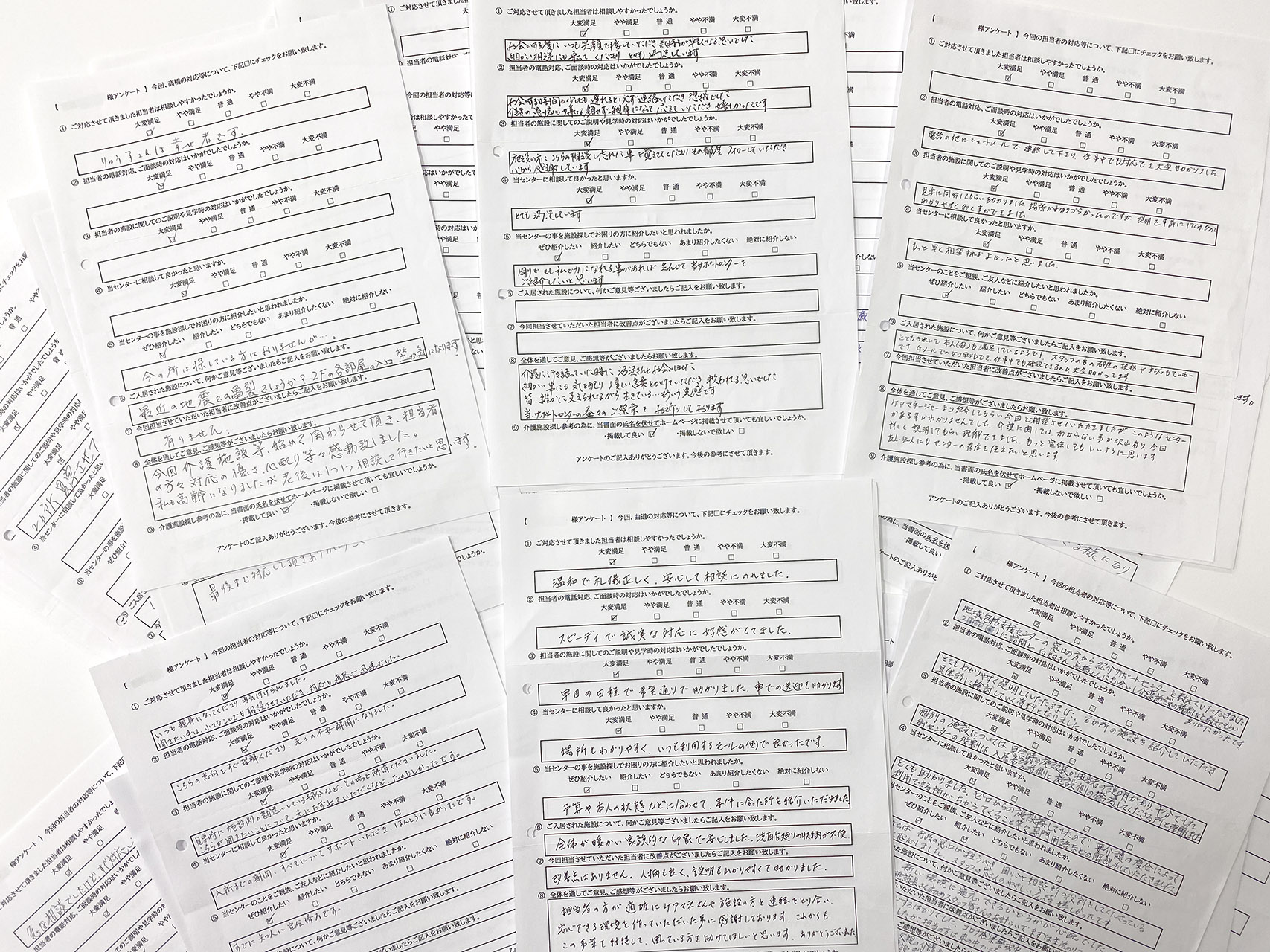 Collection of handwritten Japanese survey forms scattered across a surface, showing questions, checkboxes, and filled-in responses.