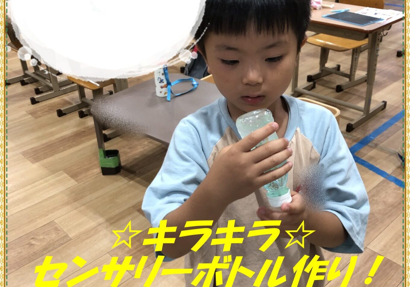 A young boy in a classroom concentrates on a science activity while holding a light-blue plastic bottle, with desks and other students in the background.