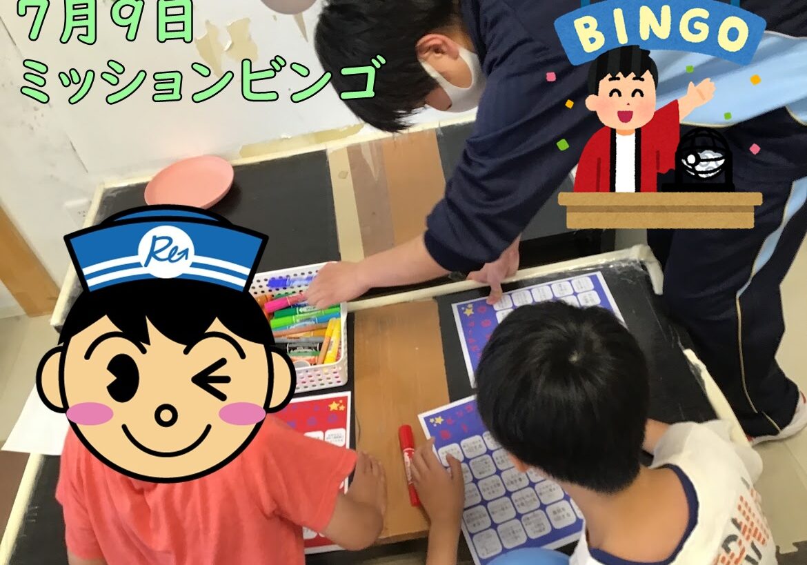 Classroom scene: kids at a table playing a July 9 mission bingo activity with bingo cards and markers; Japanese banner text reads '7月9日 ミッションビンゴ'