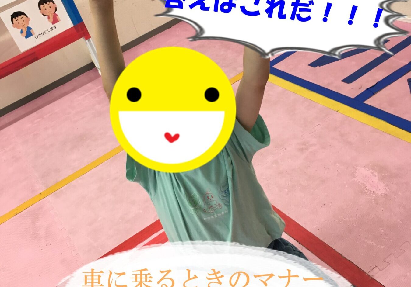 Child kneels on a pink gym floor, holding a paper with a blue X above, while a large speech-bubble-style caption in Japanese reads '答えはこれだ!!!' and a banner at the bottom mentions '車に乗るときのマナー OXゲーム' (an O/X game about car manners); the child's face is covered with a smiley emoji.